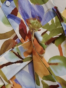 Close-up of floral print dress featuring a waist belt with a golden D-ring metal buckle