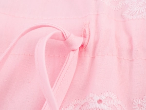 Detail of pink cotton dress showing white floral embroidery and drawstring waist