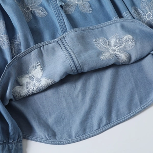 Détail de la broderie florale blanche sur l'ourlet en jean bleu clair décontracté