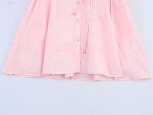 Detail of pink cotton dress with white floral embroidery and drawstring metal tips