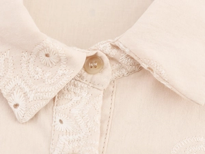Detail of embroidered lapel collar and button on apricot sleeveless mini dress