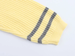 Close-up of light yellow ribbed knit sleeve cuffs with grey striped detailing