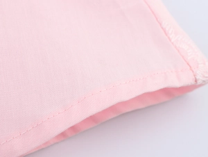 Detailed macro view showing the fine stitching and side edge seams on a pink embroidered dress