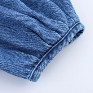 Gros plan d'une chemise en jean bleue montrant les poignets bouffants et les coutures