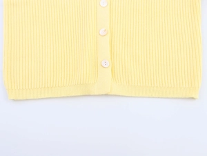 Detailed macro view of yellow ribbed knit cardigan with ivory buttons and soft texture