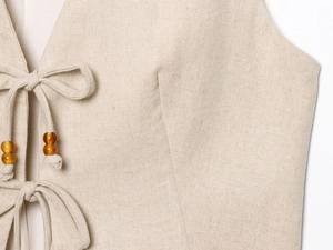 Close-up of beige linen vest featuring lace-up ties with decorative wooden beads