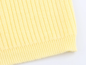 Macro shot of light yellow ribbed knit hem detailing the fine texture of the cardigan