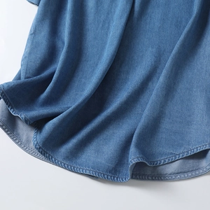Macro detail of curved hem and stitching on blue Tencel denim short sleeve shirt