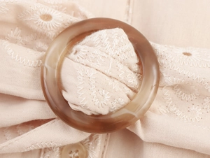 Detail of summer mini dress showing amber resin buckle and white wave embroidery