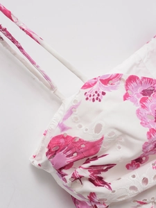 Close-up of white cotton fabric with pink floral embroidery and eyelet details
