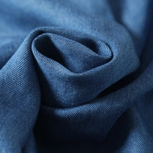 Macro view of blue tencel denim fabric showing soft twill texture and fabric folds