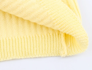 Detail of light yellow knit cardigan showing neat flat stitch and ribbed hem texture