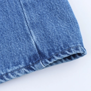 Macro du tissu en denim bleu montrant le tissage sergé et les détails de couture soignés
