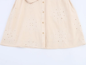 Macro view of cream eyelet floral embroidery and button placket on a sleeveless dress