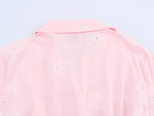 Detail of pink summer dress featuring intricate white floral embroidery and eyelet texture