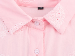 Détail du col brodé rose avec des motifs délicats en dentelle blanche et bouton en résine