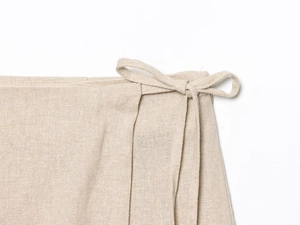 Macro detail of beige cotton linen fabric texture with tie-knot bow and refined stitching