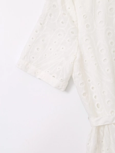 Detailed close-up of white eyelet embroidery and hollowed-out patterns on summer dress