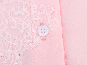 Détail du tissu brodé rose avec bouton blanc et finitions de couture de qualité
