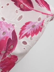 Close-up of floral print and intricate eyelet embroidery on a white summer top