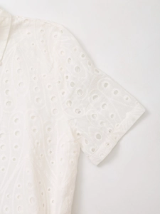 Detailed close-up of white eyelet embroidery and geometric hollow patterns on the sleeve