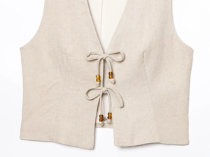 Detail view of beige cotton linen vest top with beaded drawstring ties and V-neckline