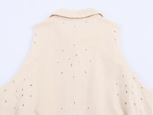 Detailed view of beige sleeveless dress featuring intricate floral hollow embroidery