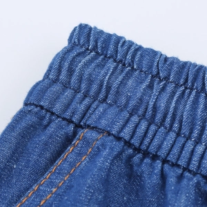 Detail of high waist drawstring on loose fit dark blue denim harem pants with orange stitching