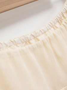 Dettaglio dello scollo elasticizzato e della trama a pieghe su gonna midi crema