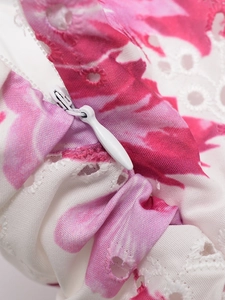 Macro detail of hidden zipper and delicate eyelet embroidery with floral print fabric