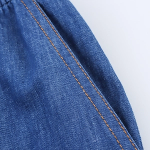 Detailed close-up of blue denim waist pocket with durable orange double-stitched seams