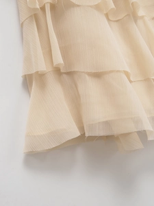 Dettaglio di balze a strati su una gonna midi color crema a vita alta in chiffon