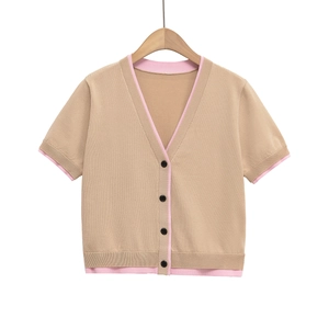 Détail du cardigan en maille avec col en V, bordures contrastées et boutons noirs