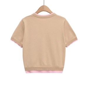 Détail de gilet en maille camel montrant les bords roses contrastés et la texture