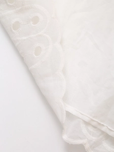 Close-up of white broderie anglaise embroidery with scalloped edges on the dress fabric
