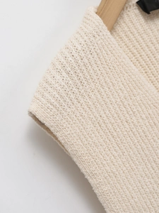 Gros plan sur le tissu du gilet en maille crème montrant la texture côtelée fine et le cintre