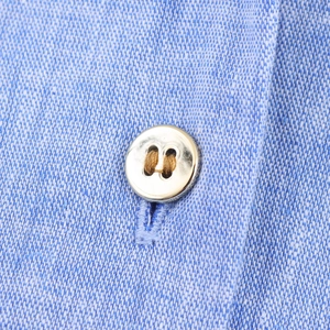 Détail macro de la texture du tissu bleu clair avec un bouton en métal doré poli