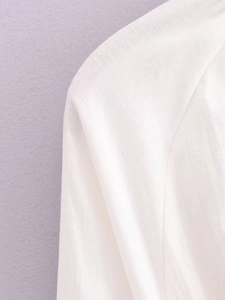 Gros plan sur le tissu blanc de la robe d'été avec texture lin respirante et pompon