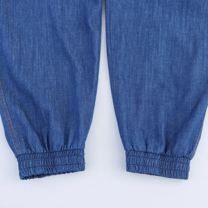 Detailed close-up of elasticized cuffs and contrast stitching on dark blue harem pants
