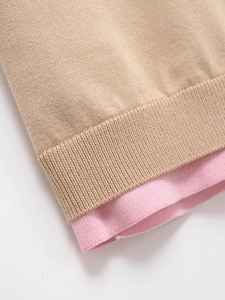 Détail des coutures contrastées kaki et rose sur les poignets en tricot côtelé
