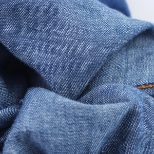 Macro shot of blue cotton fabric texture with orange contrast stitching detail