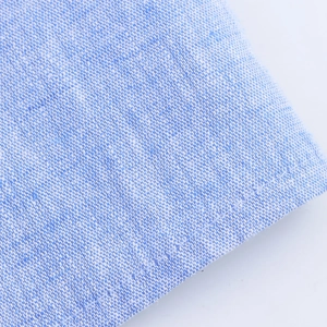 Détail du tissu tissé bleu clair avec des coutures précises sur l'ourlet de la robe