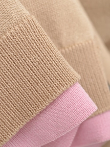 Détail du tricot côtelé sur cardigan à col en V en couleurs contrastées kaki et rose