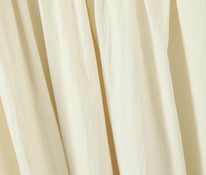 Detailed view of cream-colored pleated fabric texture on a long sleeveless dress