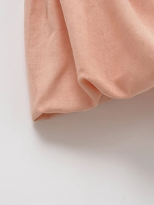 Primo piano del tessuto in cotone lino rosa cipria con trama fine e drappeggio naturale