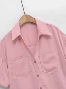 Close-up of pink short-sleeve shirt with lapel collar, square pockets, and wood buttons