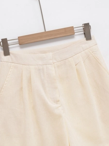 Detail of cream high-waisted shorts featuring pleated design and cotton linen texture