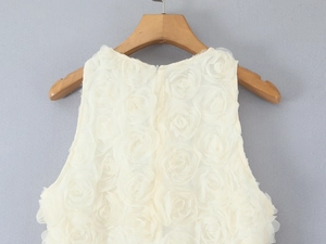 Detailed view of white sleeveless dress with 3D floral lace and elegant round neckline