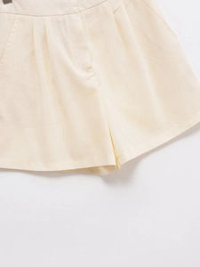 Detail view of high-waisted beige linen shorts with pleats and side pockets