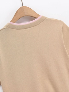 Détail du cardigan en maille beige avec coutures contrastées roses sur le col